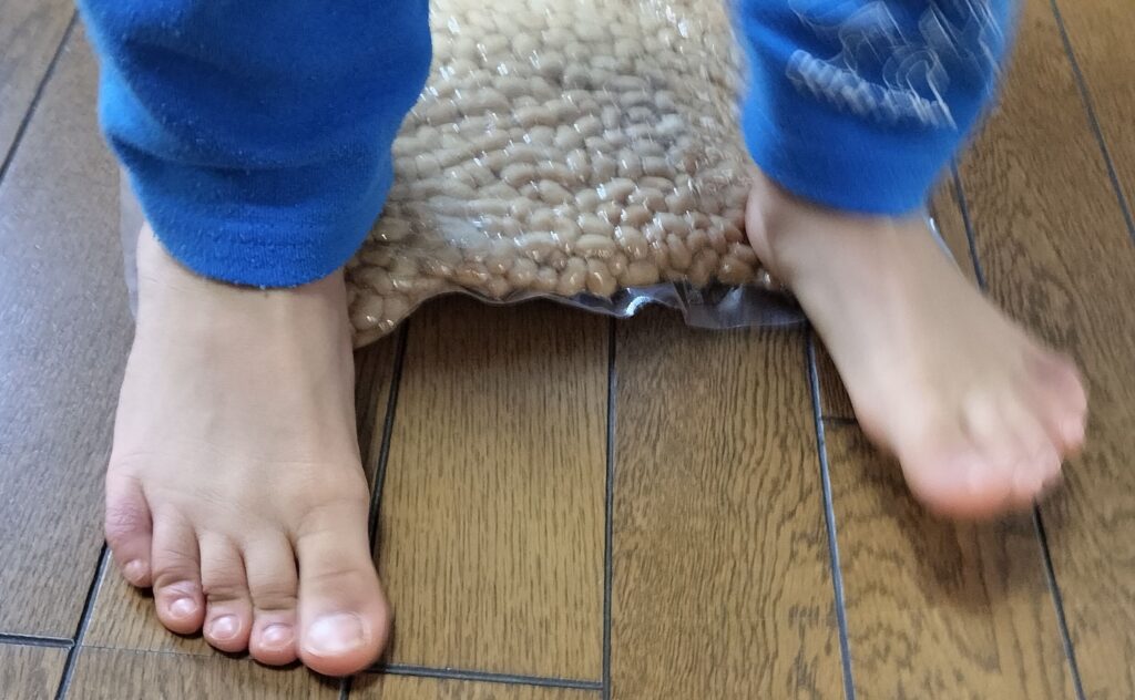 小学生の子どもが煮豆を踏んで潰している様子。味噌仕込みの工程の楽しいところです。