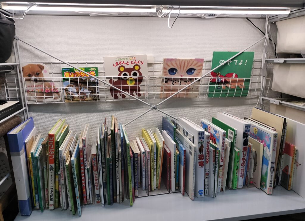 2歳の子が自分で絵本を選べるように改造した絵本棚。無印のスチールユニットシェルフに表紙が見える収納と照明を設置している様子
