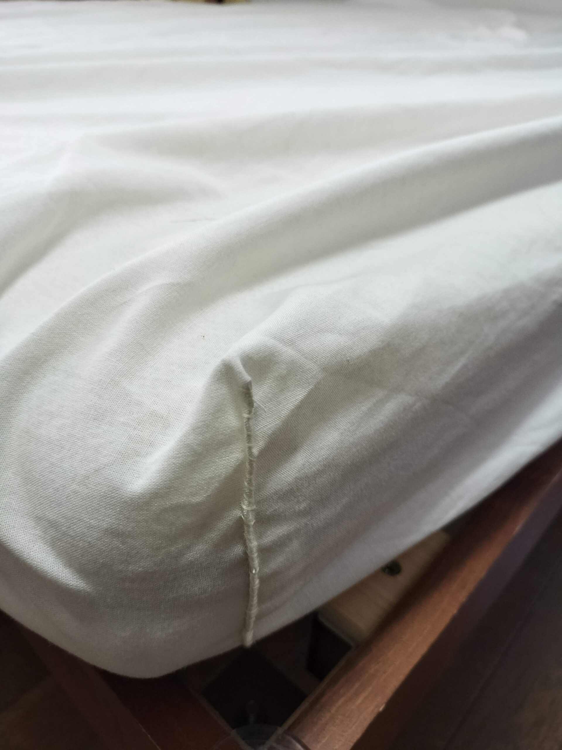 フラットシーツをボックスシーツに手縫いで縫い合わせた角の縫い目アップ