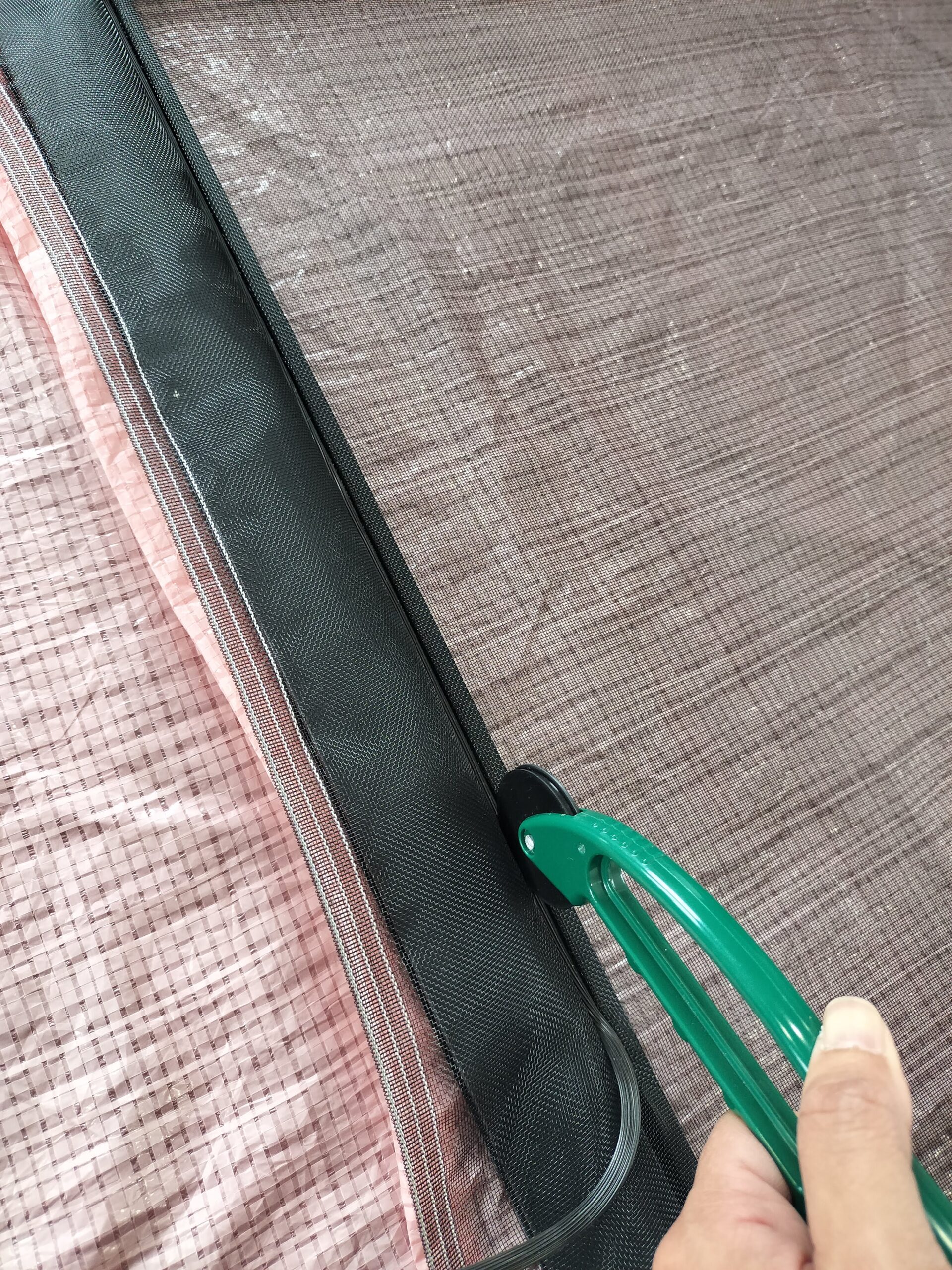 ローラーを使ってゴムで網を溝に押し込む作業の様子