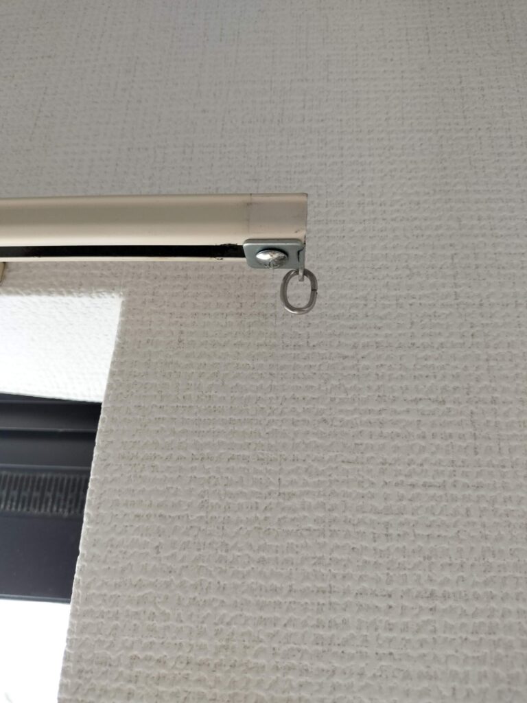 カーテンレール端に残ったキャップストップの金具。プラスチックカバーが割れてなくなった状態