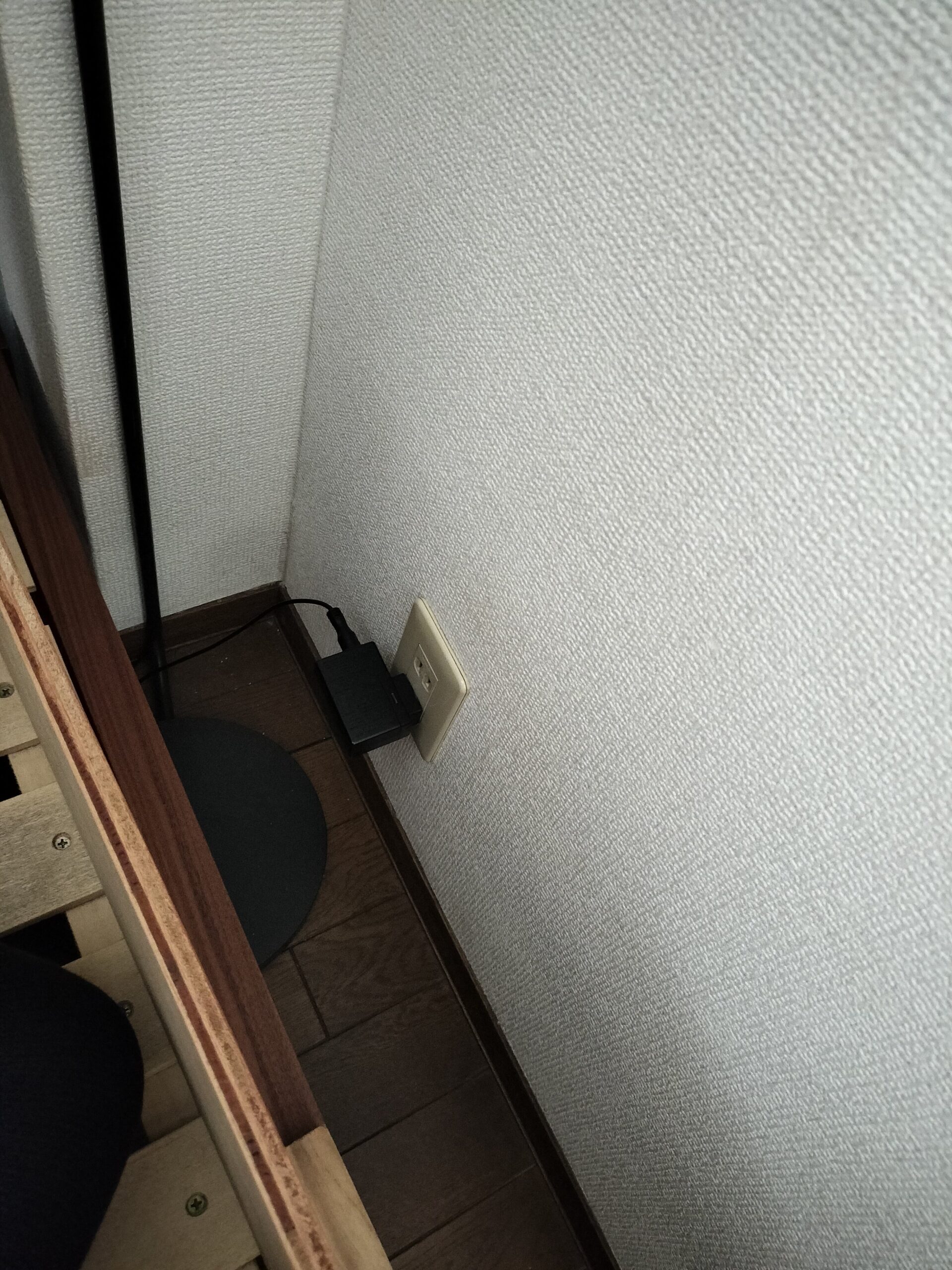 ベッドのすのこフレーム越しに壁のコンセントが見えている状態。18cmの隙間が丸見えになっている
