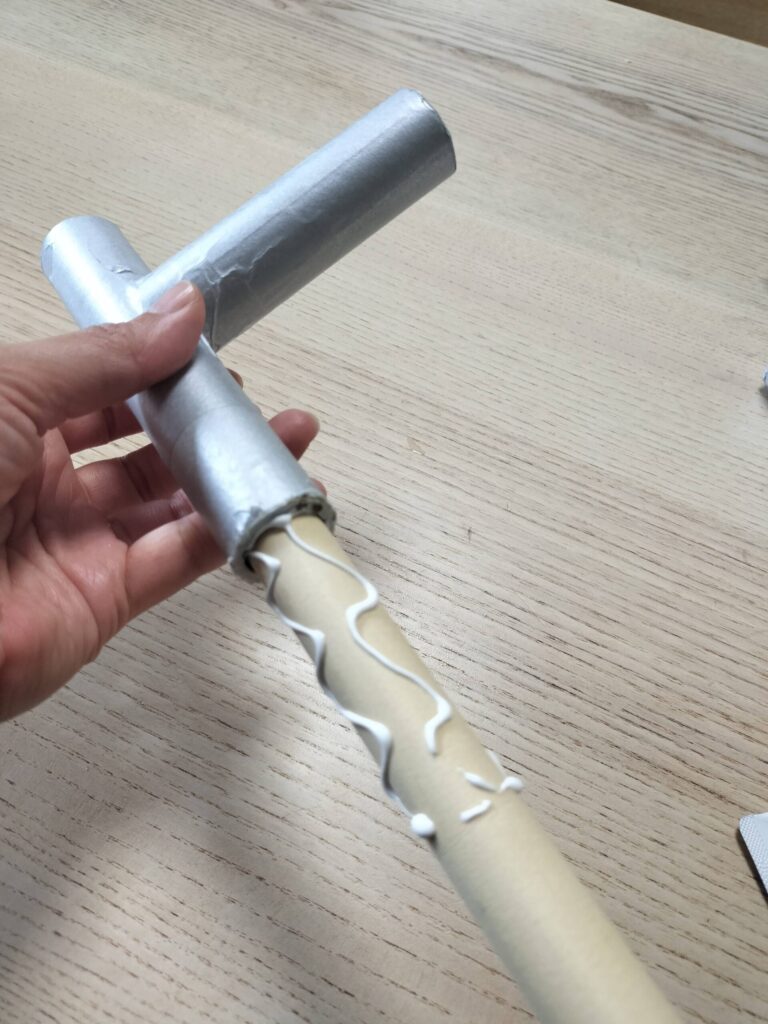 ボンドを塗った棒をラップの芯で作ったままごと用蛇口に差し込んで補強するところ。