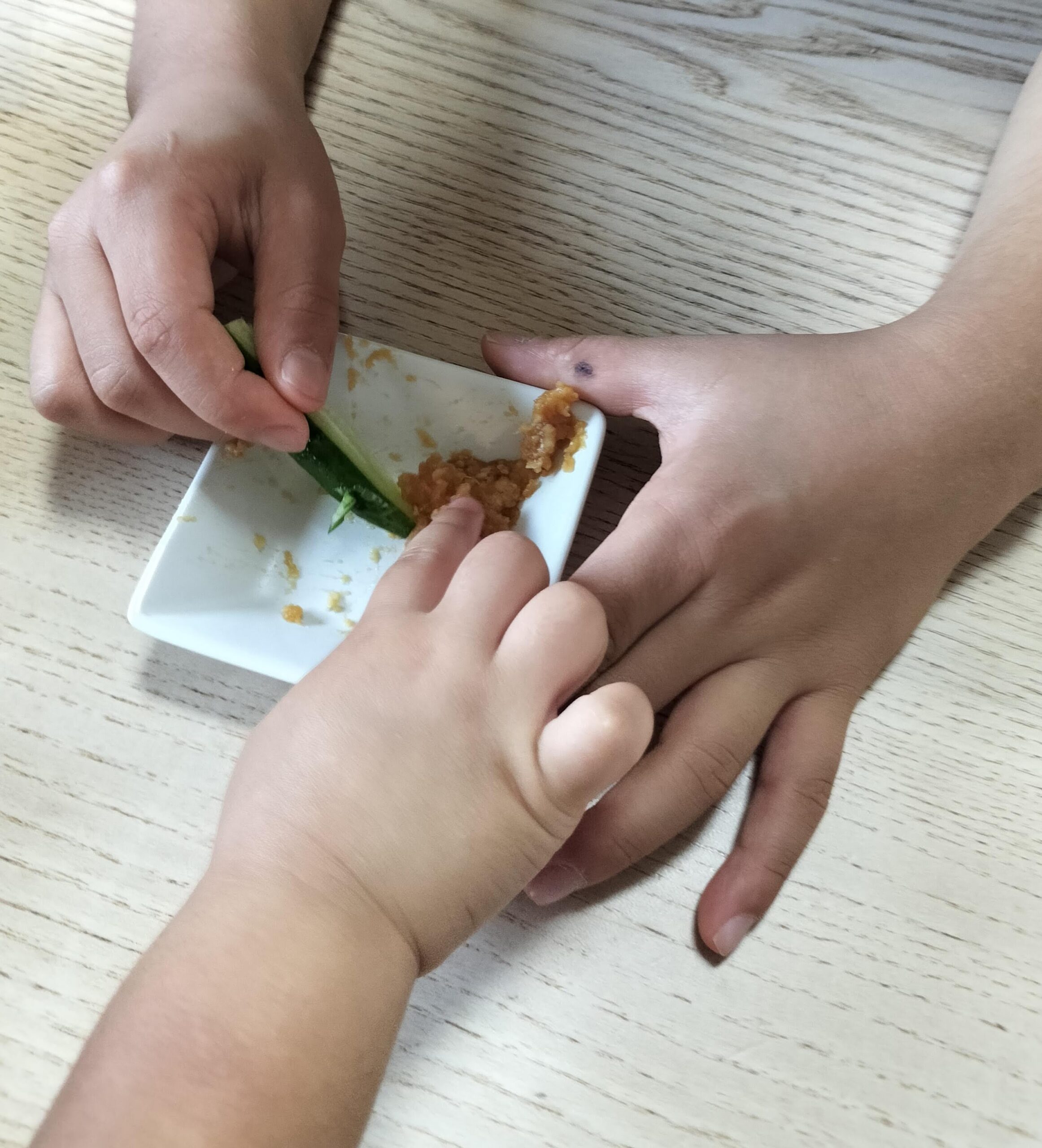 きゅうりにつけて味噌を味見する子どもの手