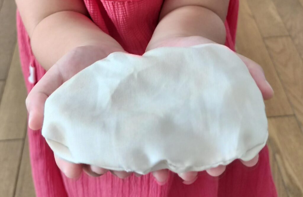 手作りしたままごとの巾着型の食材を見せる子ども