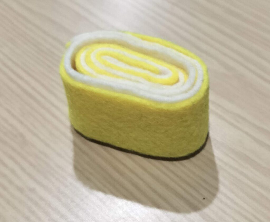 黄色と白のフェルトで作った渦巻き状の卵焼き(伊達巻風)の食材
